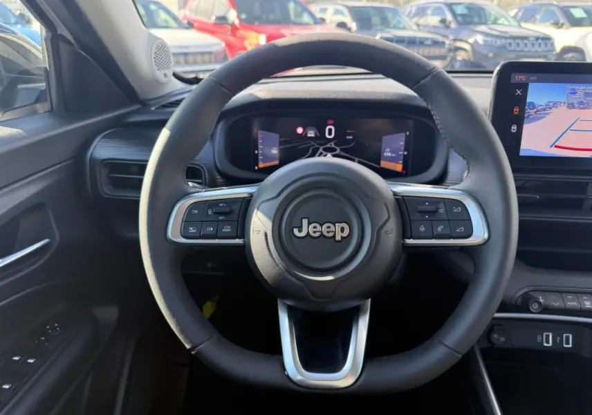 Vue intérieure centrée sur le volant Jeep noir avec tableau de bord numérique et écran multimédia affichant la caméra de recul.