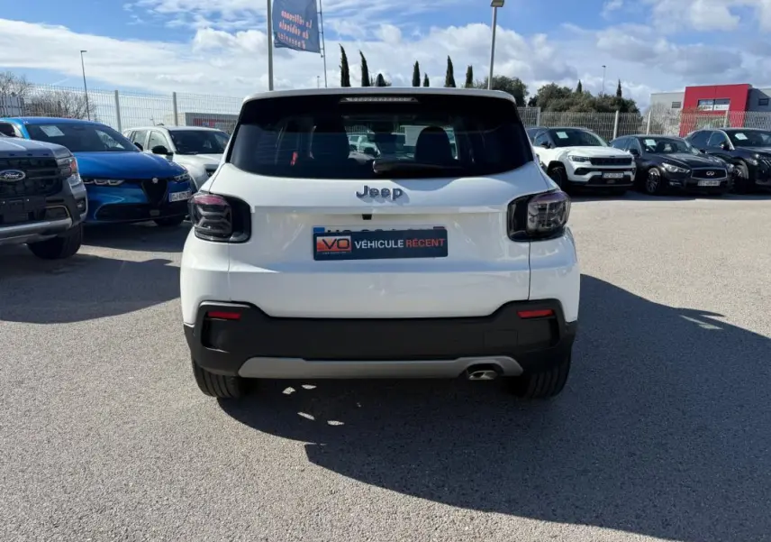 Vue arrière d'un Jeep Avenger blanc 2025 avec feux arrière fumés et pare-chocs noir contrastant.