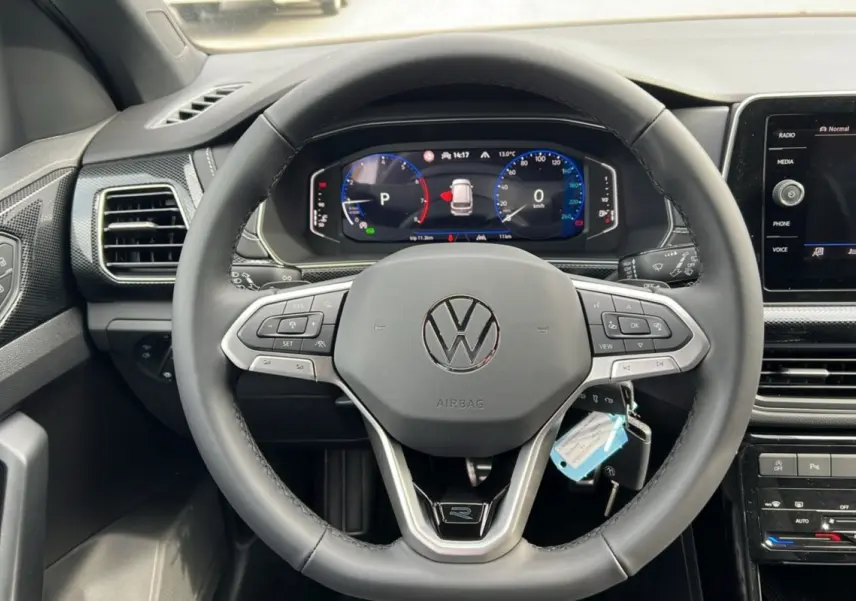Vue rapprochée du volant cuir multifonctions noir du Volkswagen T-Cross TSI 116 DSG7 R-Line avec tableau de bord digital.