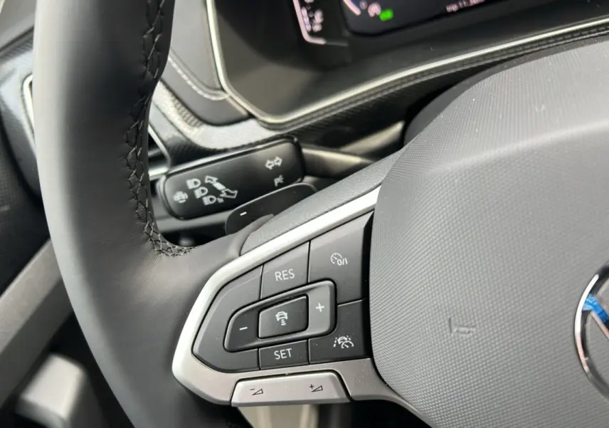 Gros plan sur le volant cuir multifonctions du Volkswagen T-Cross gris argent, avec commandes de régulateur de vitesse.
