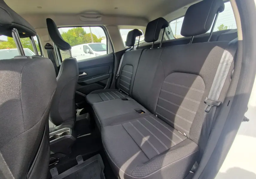 Vue intérieure côté droit des sièges arrière noirs du Dacia Duster 4x4 blanc, montrant les appuie-têtes et ceintures de sécurité.
