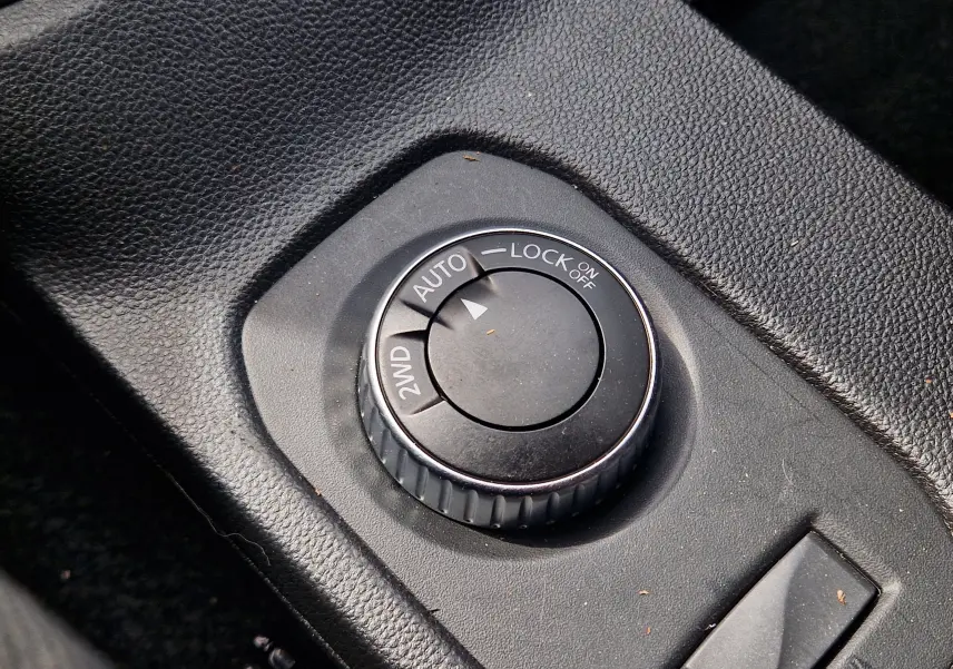 Gros plan sur la molette de sélection du mode 4x4 dans l'habitacle du Dacia Duster blanc, version 2022.