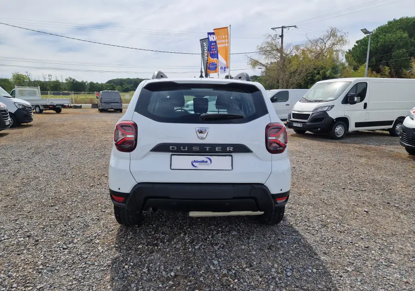 Vue arrière d'un Dacia Duster blanc 4x4 2022, avec logo et nom du modèle bien visibles sur le hayon.