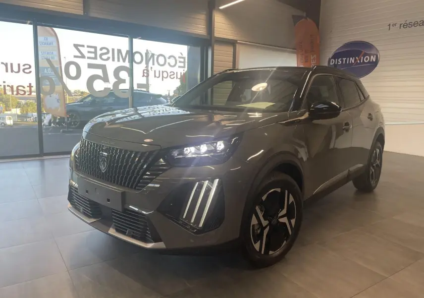 Peugeot 2008 gris métallisé en 3/4 avant droit, avec calandre noire et feux LED 3 griffes allumés en showroom.