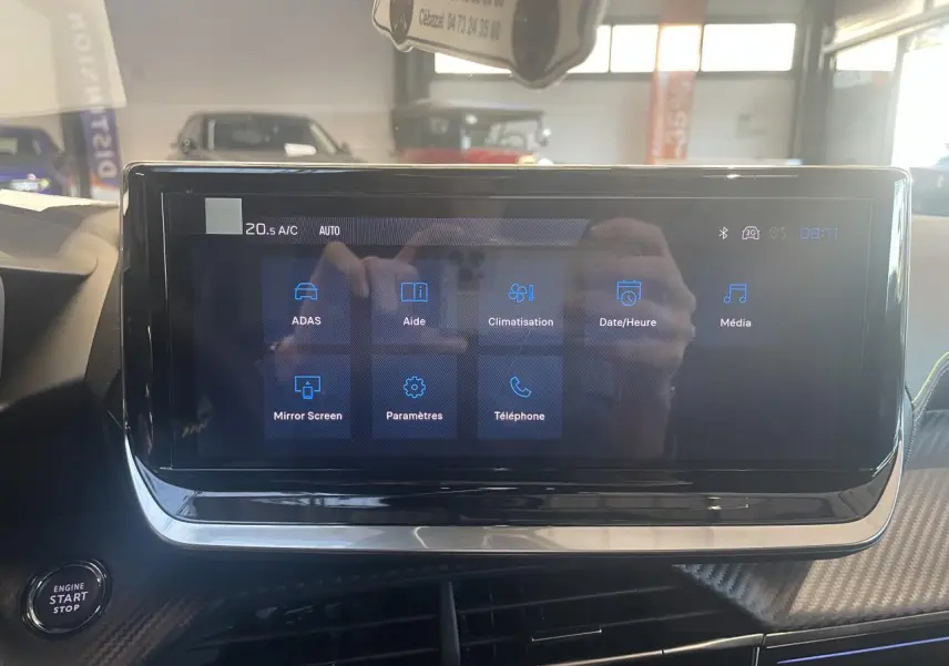 Écran tactile central du Peugeot 2008 1.2i Hybrid 2026 affichant les menus ADAS, climatisation et multimédia, intérieur noir.