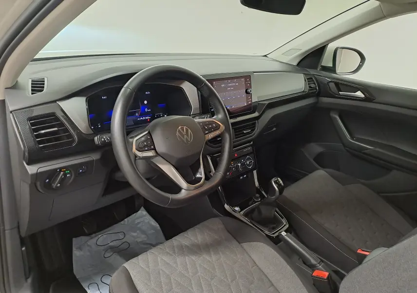 Vue intérieure côté conducteur du Volkswagen T-Cross 2024, tableau de bord moderne avec volant multifonction et boîte manuelle.