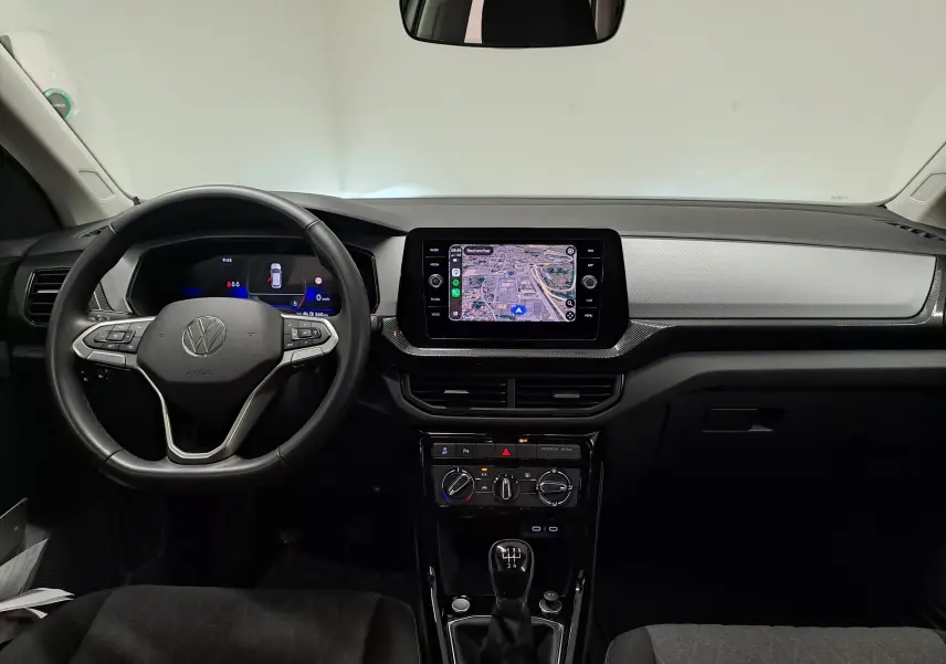 Vue intérieure frontale du tableau de bord du Volkswagen T-Cross 2024 avec écran tactile et volant multifonction noir.