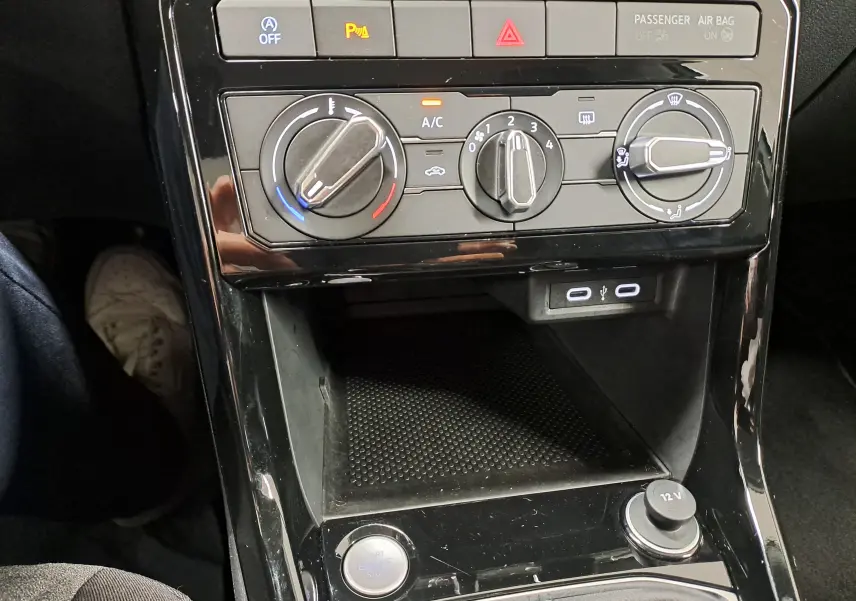 Vue rapprochée de la console centrale du Volkswagen T-Cross 2024 avec commandes manuelles de climatisation et prises USB.