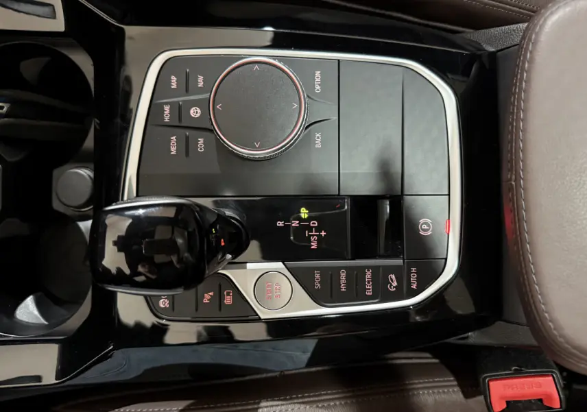 Gros plan sur la console centrale noire et boutons de commande du levier de vitesse du BMW X3 bleu hybride 2023.