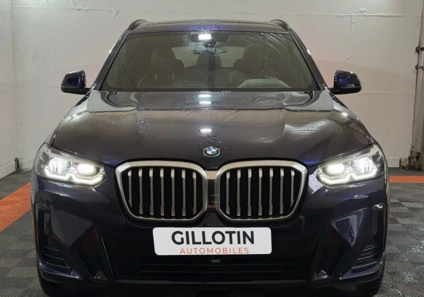 Vue frontale d'un BMW X3 xDrive30e bleu avec phares LED allumés et calandre double haricot caractéristique.