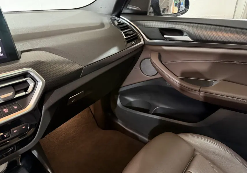 Intérieur côté passager du BMW X3 xDrive30e 2023, avec tableau de bord noir et garniture cuir marron.
