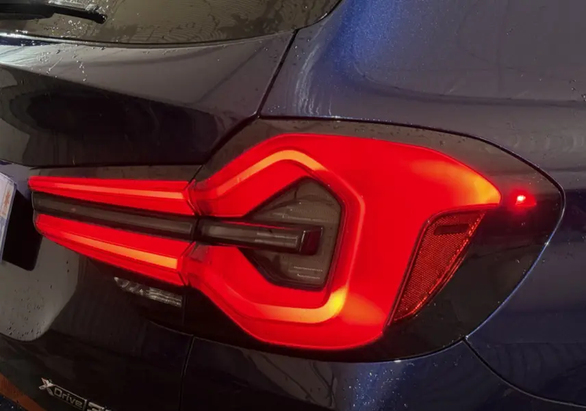 Gros plan sur le feu arrière droit rouge vif du BMW X3 xDrive30e bleu, soulignant son design lumineux distinctif.