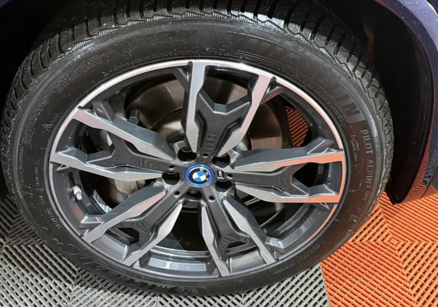 Gros plan sur la jante alliage gris foncé à design complexe du BMW X3 xDrive30e bleu 2023, avec logo central BMW.