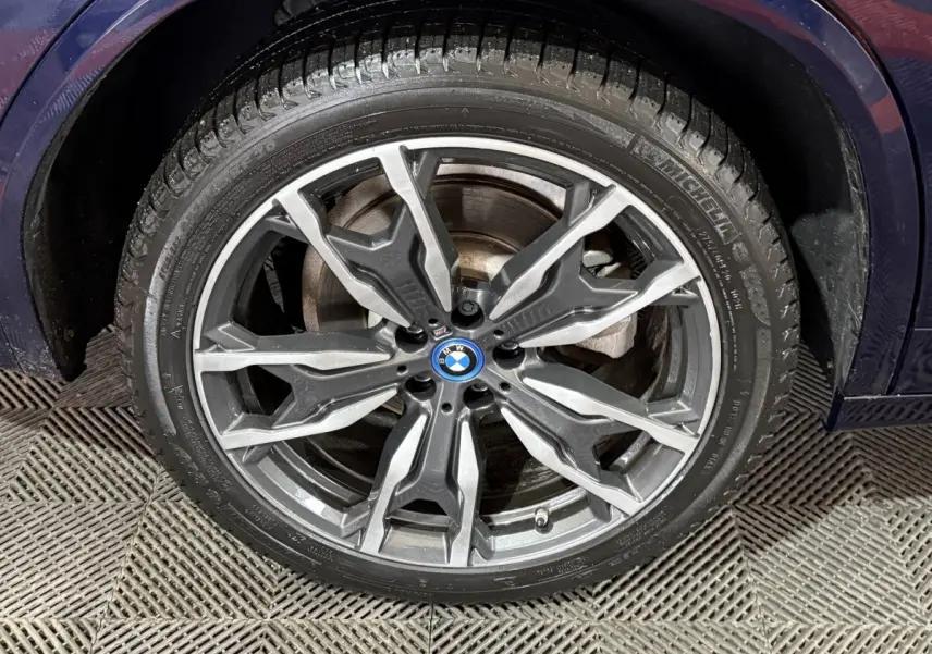 Gros plan sur la roue avant gauche du BMW X3 xDrive30e bleu 2023 avec jante alu M Sport au design moderne.