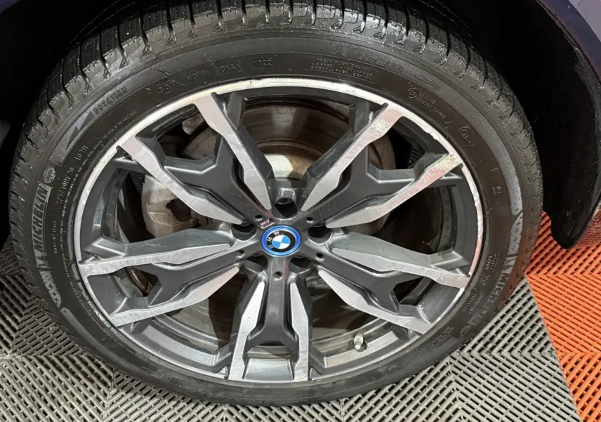 Gros plan sur la jante alliage à design complexe du BMW X3 bleu xDrive30e 2023, avec logo central BMW visible.