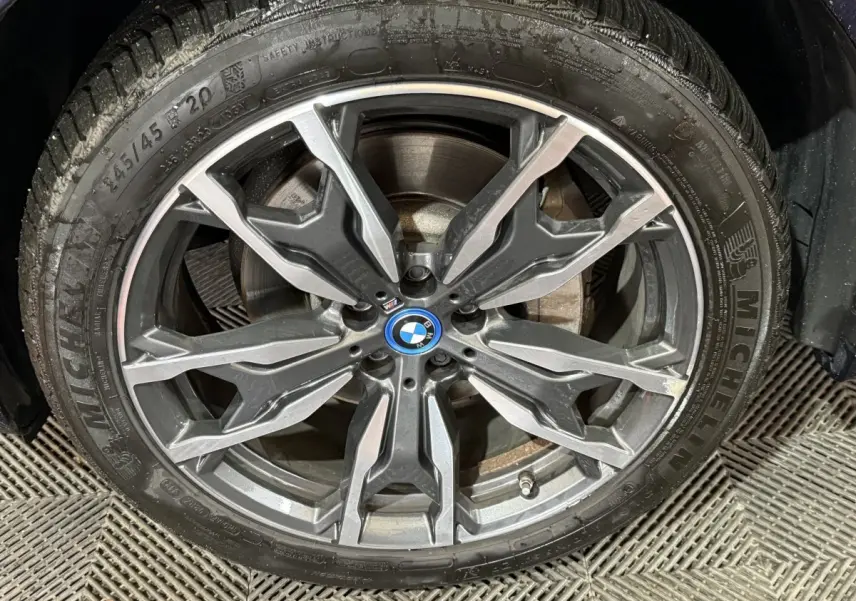 Gros plan sur la jante alliage gris foncé à double branches du BMW X3 bleu xDrive30e 2023 avec logo BMW central.