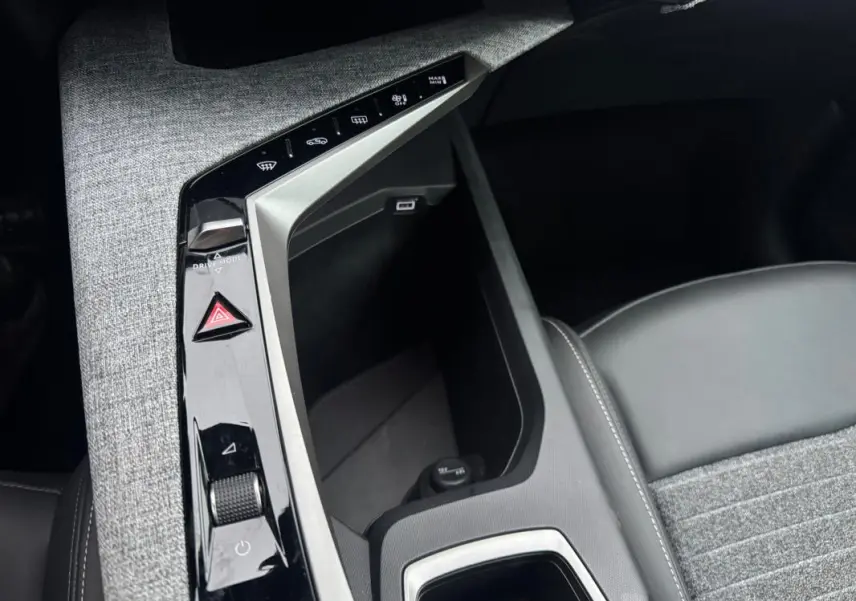 Vue rapprochée de la console centrale du Peugeot 3008 Hybrid 145 Allure 2025 avec commandes tactiles et accoudoir gris.