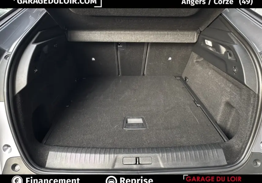 Coffre ouvert vu de l'arrière d'un Peugeot 3008 gris clair 2024, montrant un espace de chargement propre et spacieux.