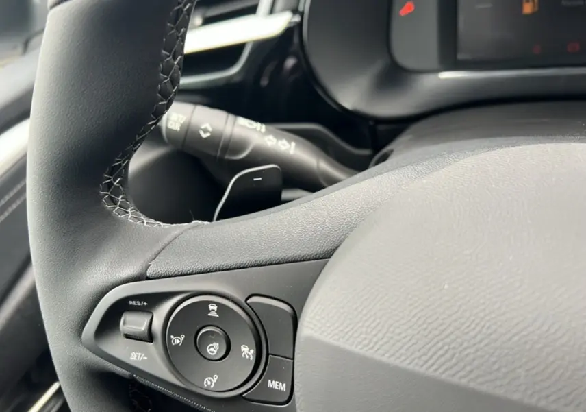 Gros plan sur le volant cuir multifonctions noir de l’Opel Corsa Hybrid 110 e-DCT6, avec commandes intégrées.