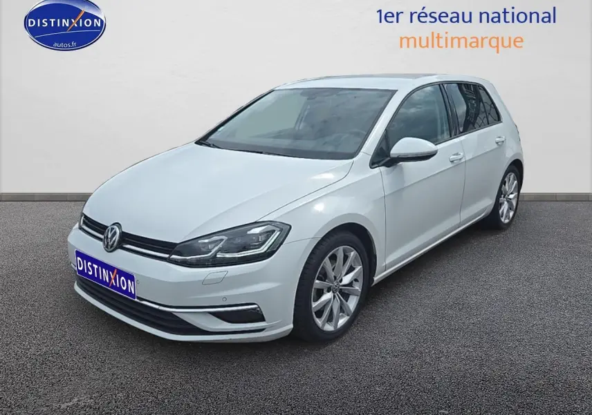 Volkswagen Golf blanche vue en 3/4 avant droit, avec jantes alu et phares LED allumés.