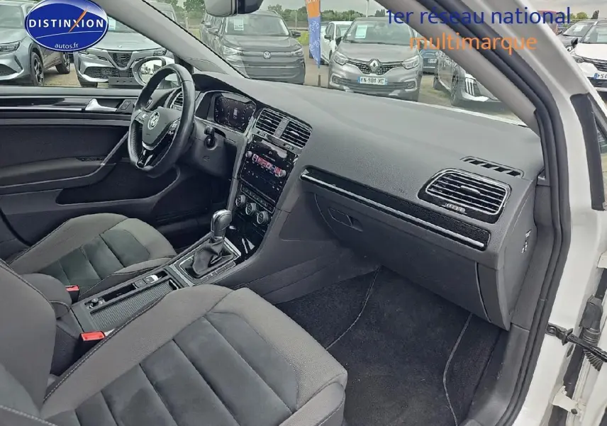 Intérieur avant droit de Volkswagen Golf blanc 2019, montrant sièges tissu et console centrale avec boîte auto.