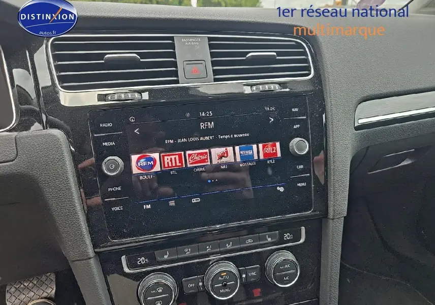 Vue rapprochée de la console centrale noire avec écran tactile et commandes de climatisation d'une Volkswagen Golf blanche.