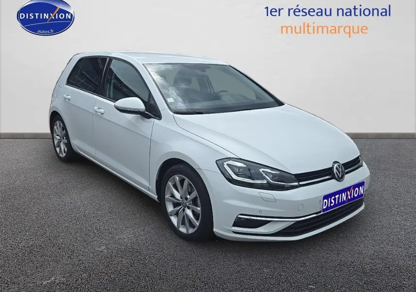 Volkswagen Golf blanc vue 3/4 avant droit avec jantes alu et phares LED allumés.