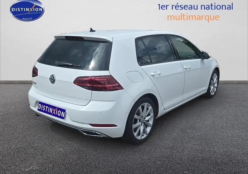 Vue 3/4 arrière droite d'une Volkswagen Golf blanche avec jantes alliage et vitres teintées.