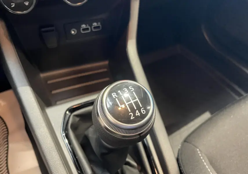 Gros plan sur le levier de vitesses manuel noir de la Renault Clio 1.5 Blue dCi gris Rafale, intérieur sombre.