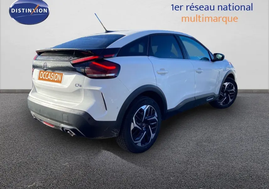 Citroën C4 blanc vue 3/4 arrière droit avec toit noir et jantes alliage bicolores sur sol gris.