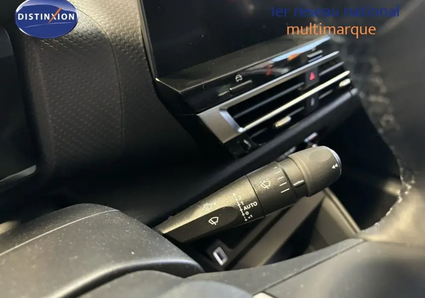 Détail du commodo d'essuie-glace dans l'habitacle du Citroën C4 blanc, avec tableau de bord et écran tactile en arrière-plan.