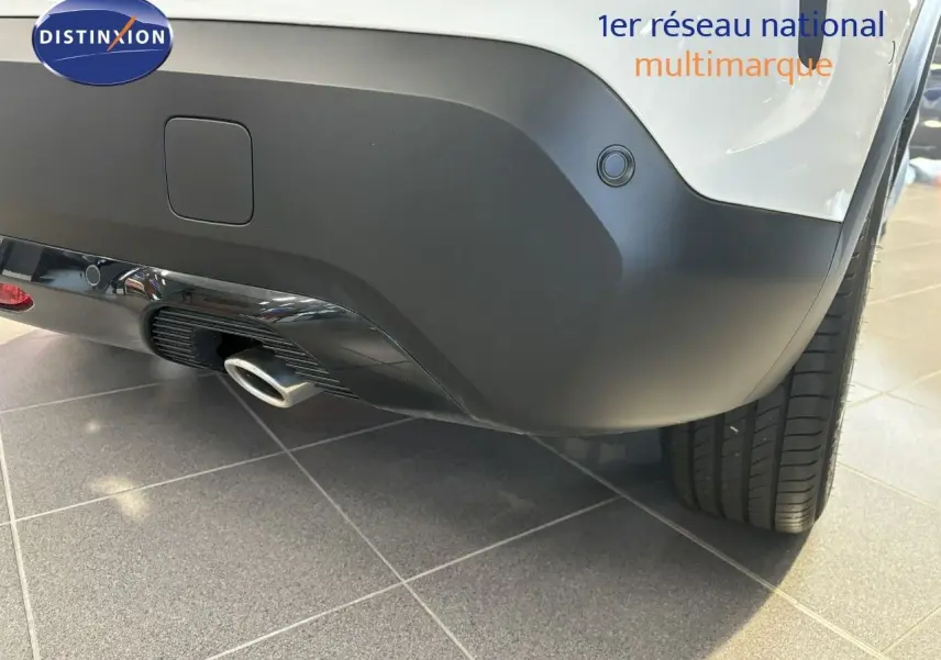 Gros plan sur le pare-chocs arrière droit blanc d'une Citroën C4 2022 avec sortie d'échappement et capteur de recul.