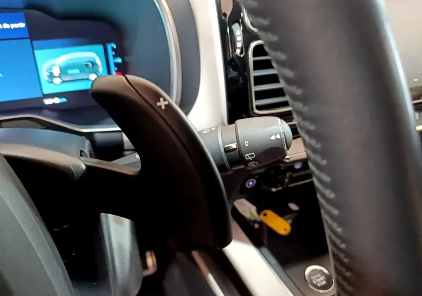 Gros plan sur la palette de changement de vitesse droite et le tableau de bord digital bleu du Citroën C5 Aircross Hybrid noir.