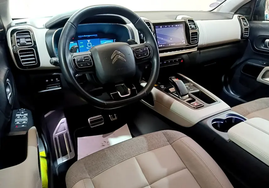 Intérieur clair du Citroën C5 Aircross Hybrid 225, vue depuis le siège conducteur sur le tableau de bord et volant cuir noir.