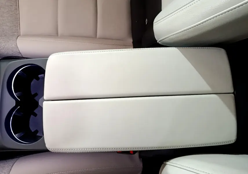 Vue plongeante sur l'accoudoir central beige et porte-gobelets du Citroën C5 Aircross Hybrid 225 ë-EAT8 Shine noir.