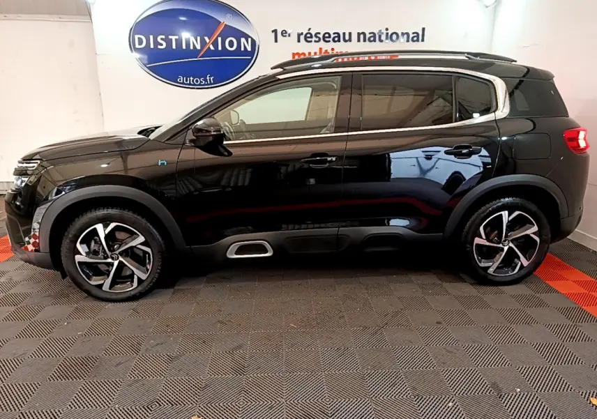Profil côté gauche d'un Citroën C5 Aircross Hybrid 225 ë-EAT8 Shine noir, avec jantes alliage et détails chromés sur les seuils.