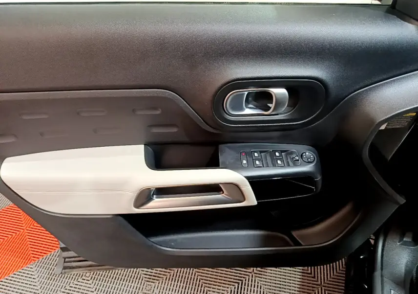 Intérieur côté gauche de la porte avant noire et beige du Citroën C5 Aircross Hybrid 225 ë-EAT8 Shine, avec commandes électriques.