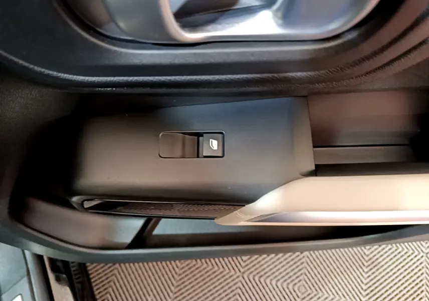Gros plan sur le bouton de commande de la vitre côté gauche dans l'habitacle noir du Citroën C5 Aircross Hybrid 225 ë-EAT8 Shine.