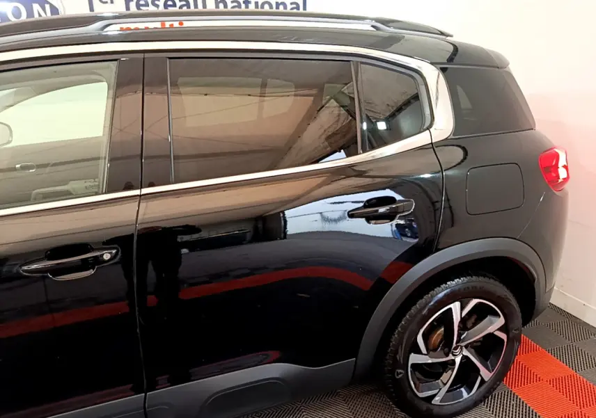 Profil côté droit noir brillant du Citroën C5 Aircross Hybrid 225 ë-EAT8 Shine avec jantes alliage et barres de toit chromées.