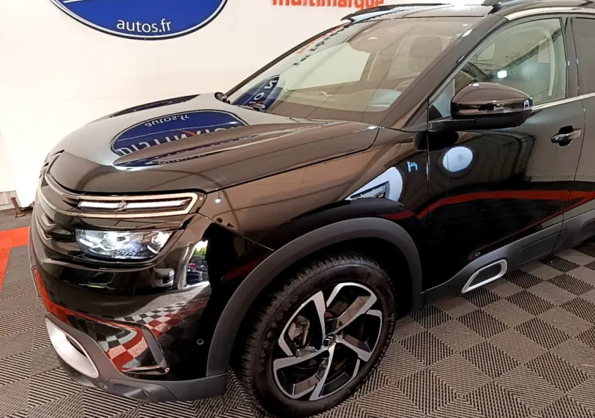 Vue 3/4 avant droit du Citroën C5 Aircross Hybrid 225 noir brillant avec jantes alliage et feux LED allumés.