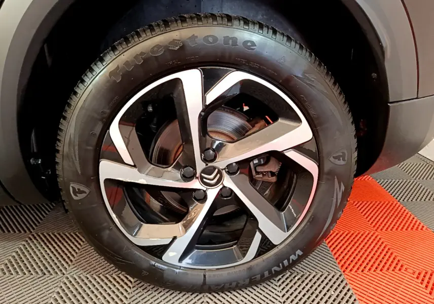 Gros plan sur la roue avant gauche du Citroën C5 Aircross Hybrid 225 ë-EAT8 Shine avec jante alliage bicolore et pneu Firestone.