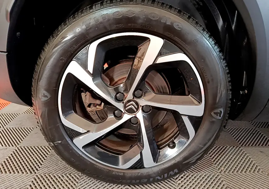 Gros plan sur la jante alliage bicolore et le pneu Firestone du Citroën C5 Aircross Hybrid 225 ë-EAT8 noir, côté arrière.