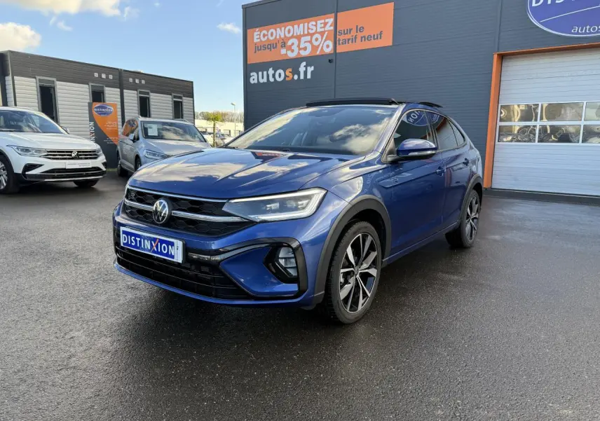 Volkswagen Taigo bleu récif métallisé en 3/4 avant droit avec jantes alliage noires brillantes sur parking.