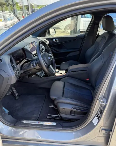 Vue intérieure côté conducteur de la BMW Série 1 118d gris foncé, avec sièges cuir et tableau de bord digital.