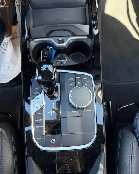 Vue plongeante sur la console centrale noire brillante de la BMW Série 1 118d Edition Sport avec levier de vitesse et molette de sélection.