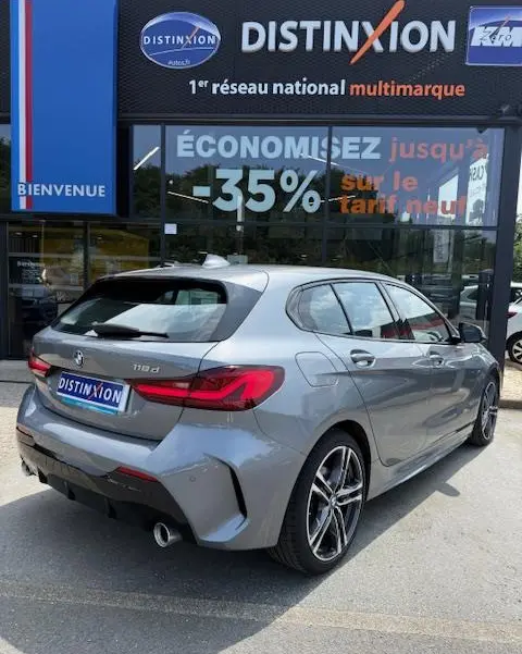 BMW Série 1 118d Edition Sport gris foncé vue 3/4 arrière droite devant un showroom Distinxion.