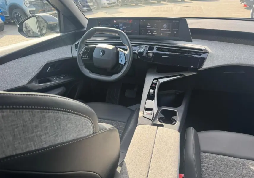 Vue intérieure avant du Peugeot 3008 Hybrid 145 Allure 2025 noir, avec cockpit numérique et sellerie tissu gris.