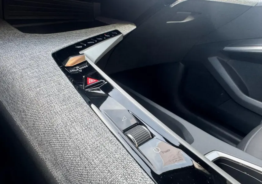 Vue intérieure rapprochée de la console centrale du Peugeot 3008 Hybrid 145 Allure 2025, avec finition tissu gris et commandes tactiles noires.