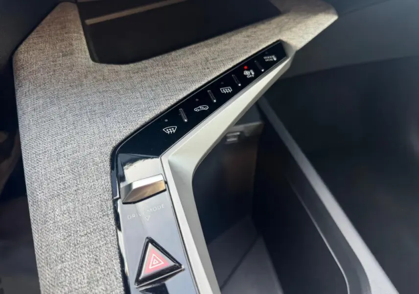 Gros plan sur la console centrale du Peugeot 3008 Hybrid 145 Allure 2025, avec boutons de contrôle et tissu gris.