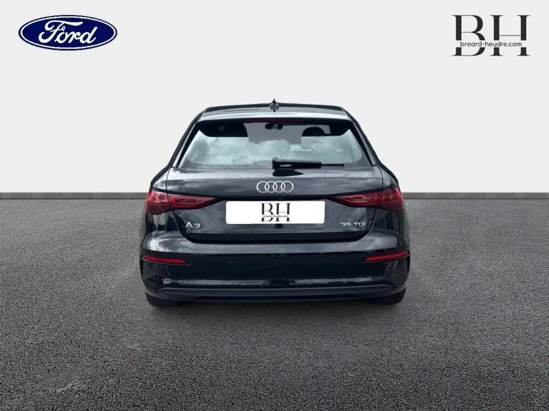 Vue arrière d'une Audi A3 Sportback 35 TDI noire Mythic métallisé, avec feux arrière LED et logo Audi visible.